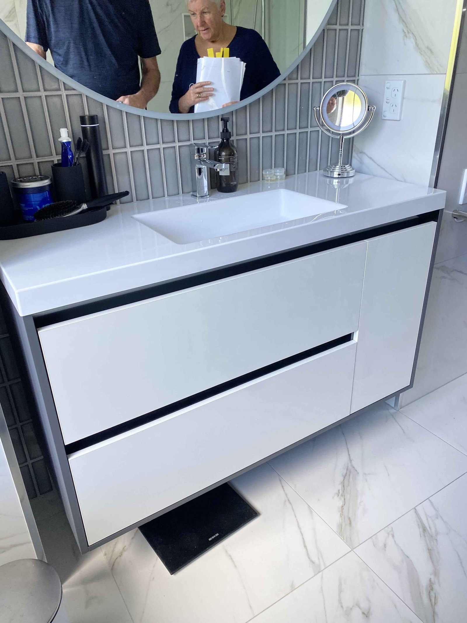 Floating vanity with drawers and a round mirror in an Alchemy bathroom renovation