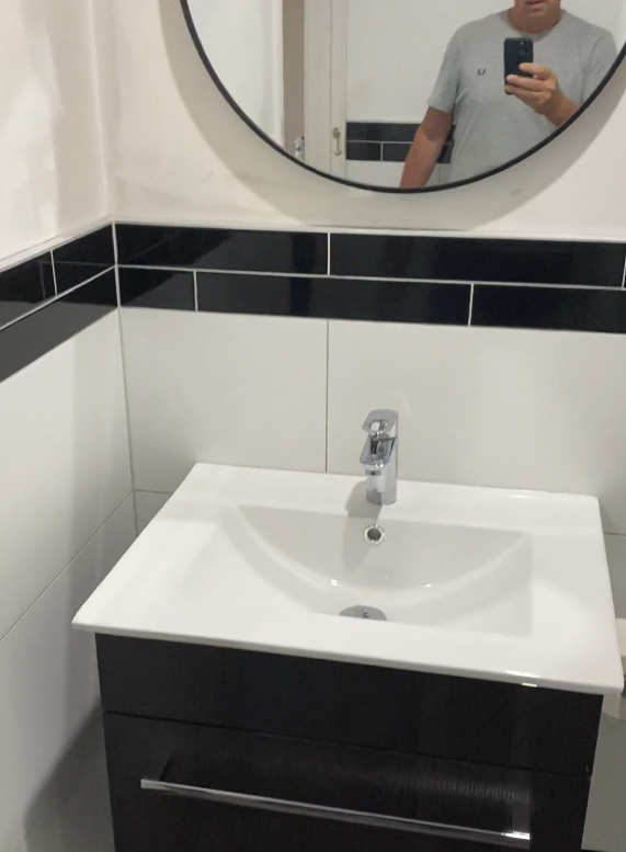 vanity ponsonby Dark vanity with a white basin and round mirror in a Ponsonby bathroom renovation