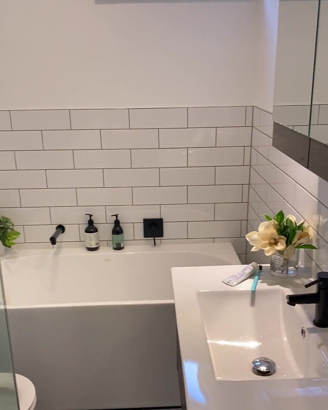 albany-bathroom-bath-vanity White bath with a matte black wall spout beside a white basin vanity, Albany bathroom renovation