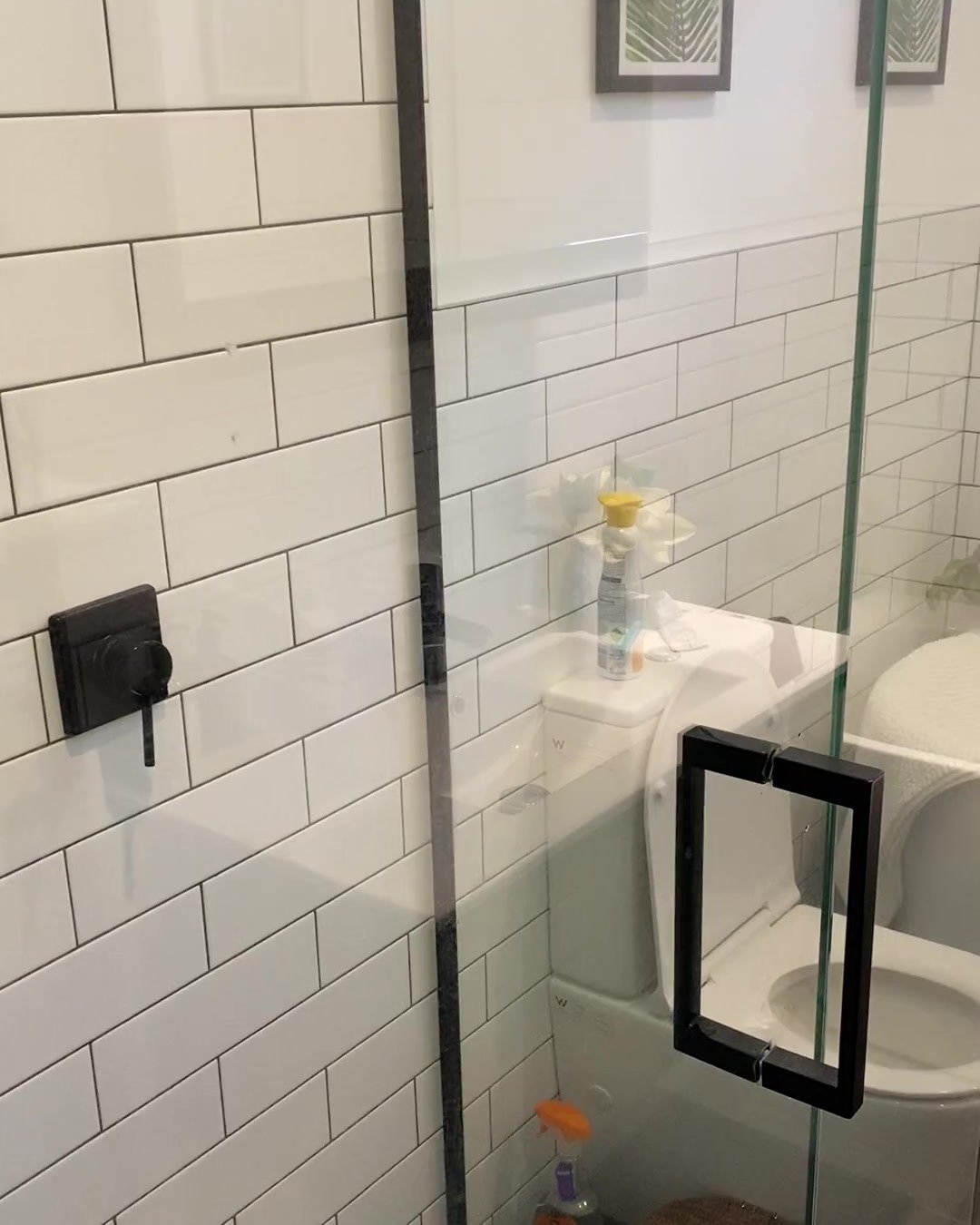 Frameless shower door with a black pull handle and white subway tiles in an Albany bathroom