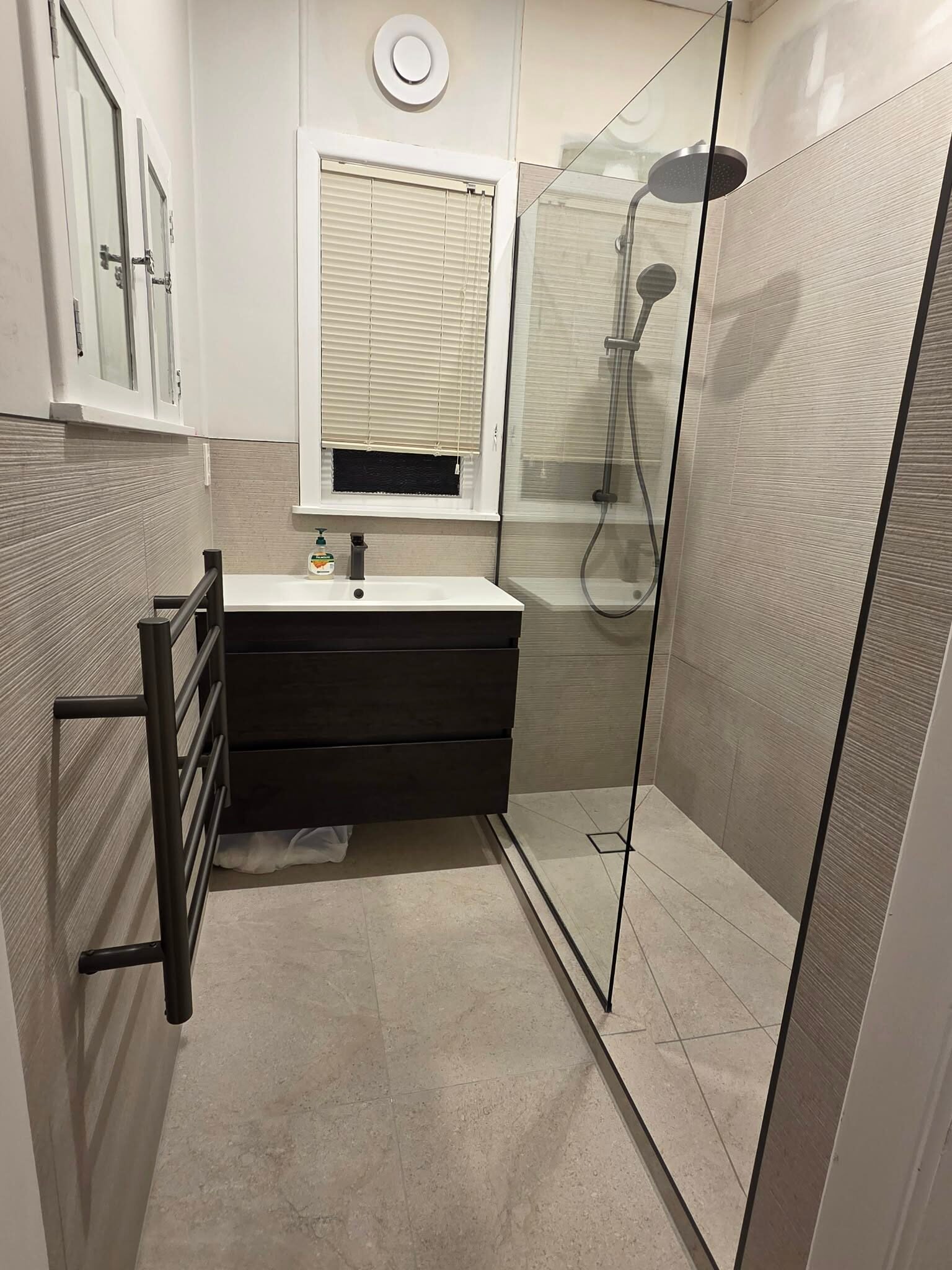 Finished bathroom with a walk-in shower, heated towel rail and dark vanity