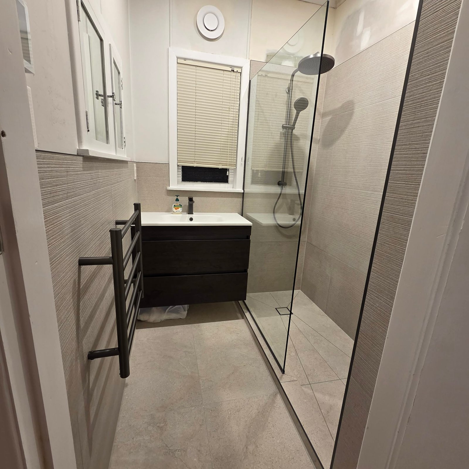 Finished bathroom with a walk-in shower, heated towel rail and dark vanity