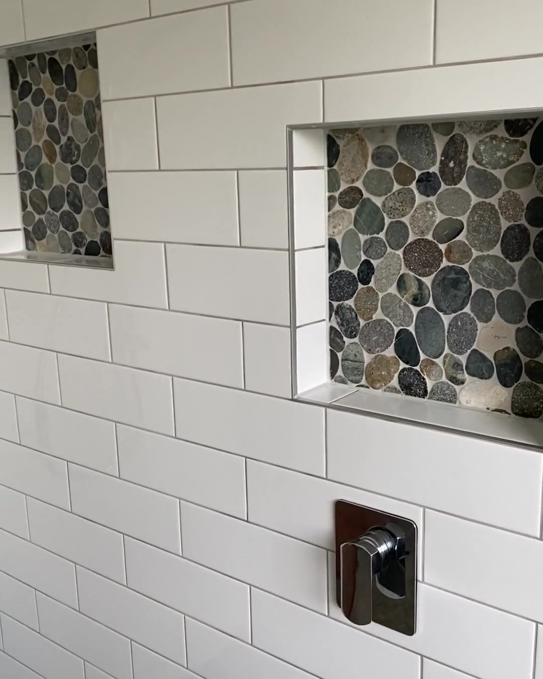 Pebble-backed shower niche above a chrome mixer in a Cockle Bay walk-in shower