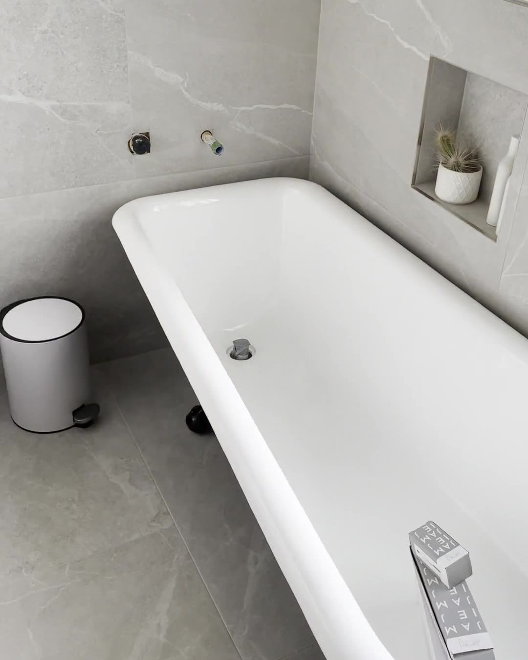 Clawfoot bath beside a recessed niche in grey stone-look tiles, Mount Eden bathroom