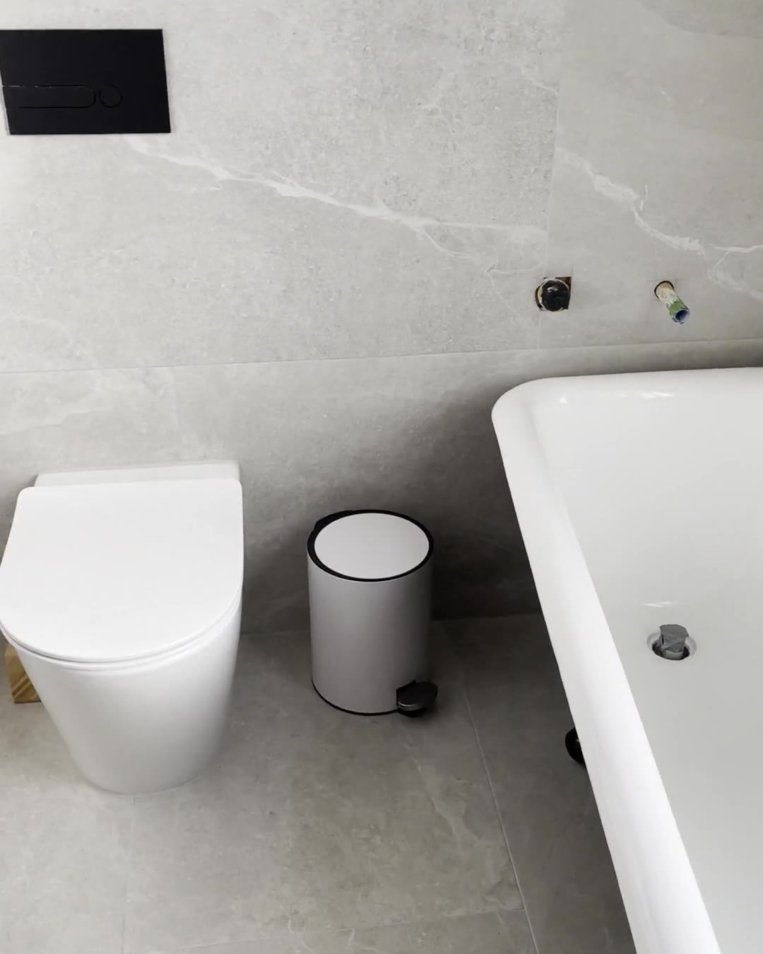 Back-to-wall toilet with a black flush plate on grey stone-look tiles, Mount Eden