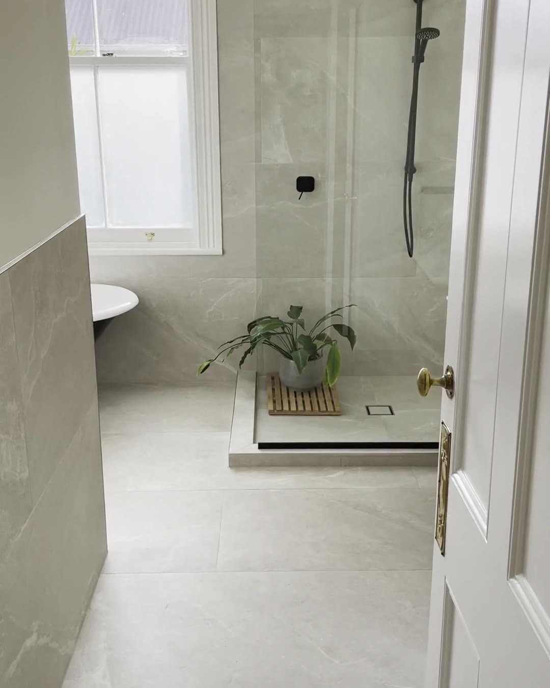 Walk-in shower and the end of a clawfoot bath seen through a panelled door, Mount Eden bathroom renovation