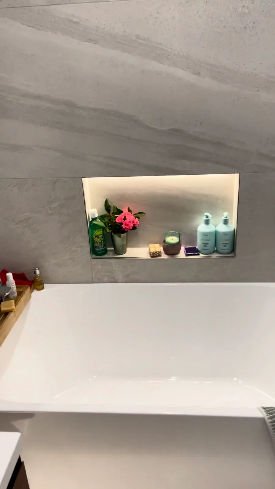 Built-in bath below a lit tiled niche with marble-look wall tiles in a Glendowie bathroom