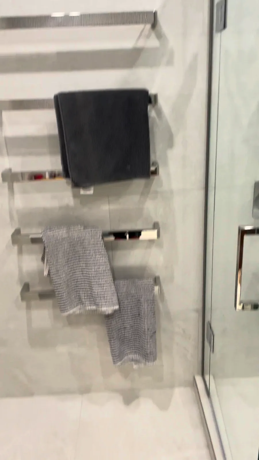 Chrome heated towel ladder beside a glass walk-in shower in a renovated Glendowie bathroom