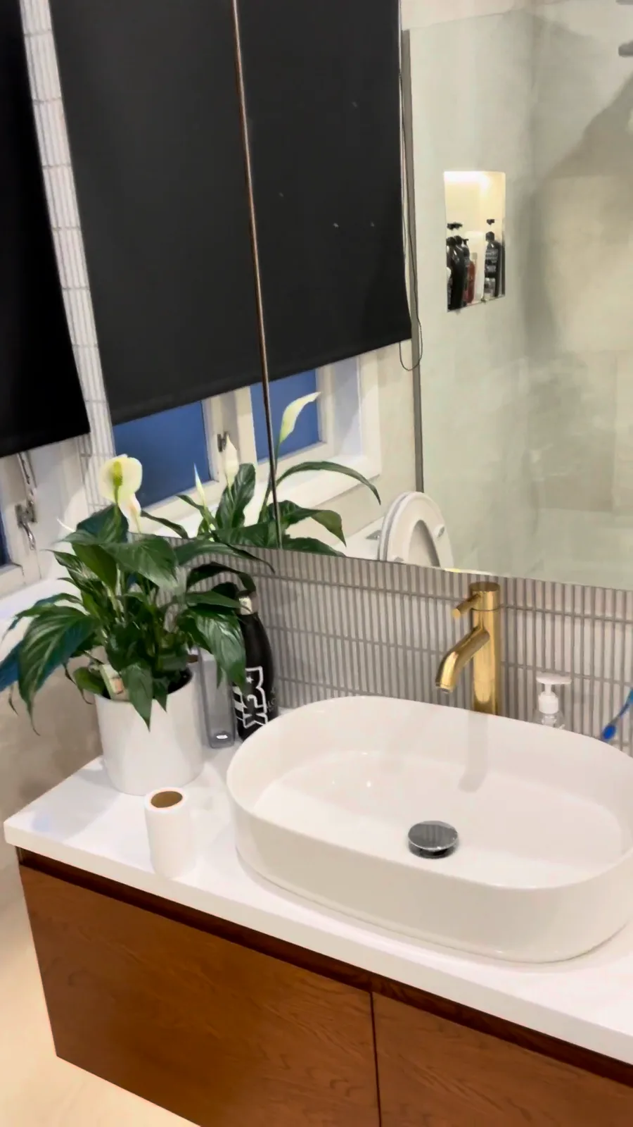 Timber wall-hung vanity with a white vessel basin and brushed brass tap in a Glendowie bathroom