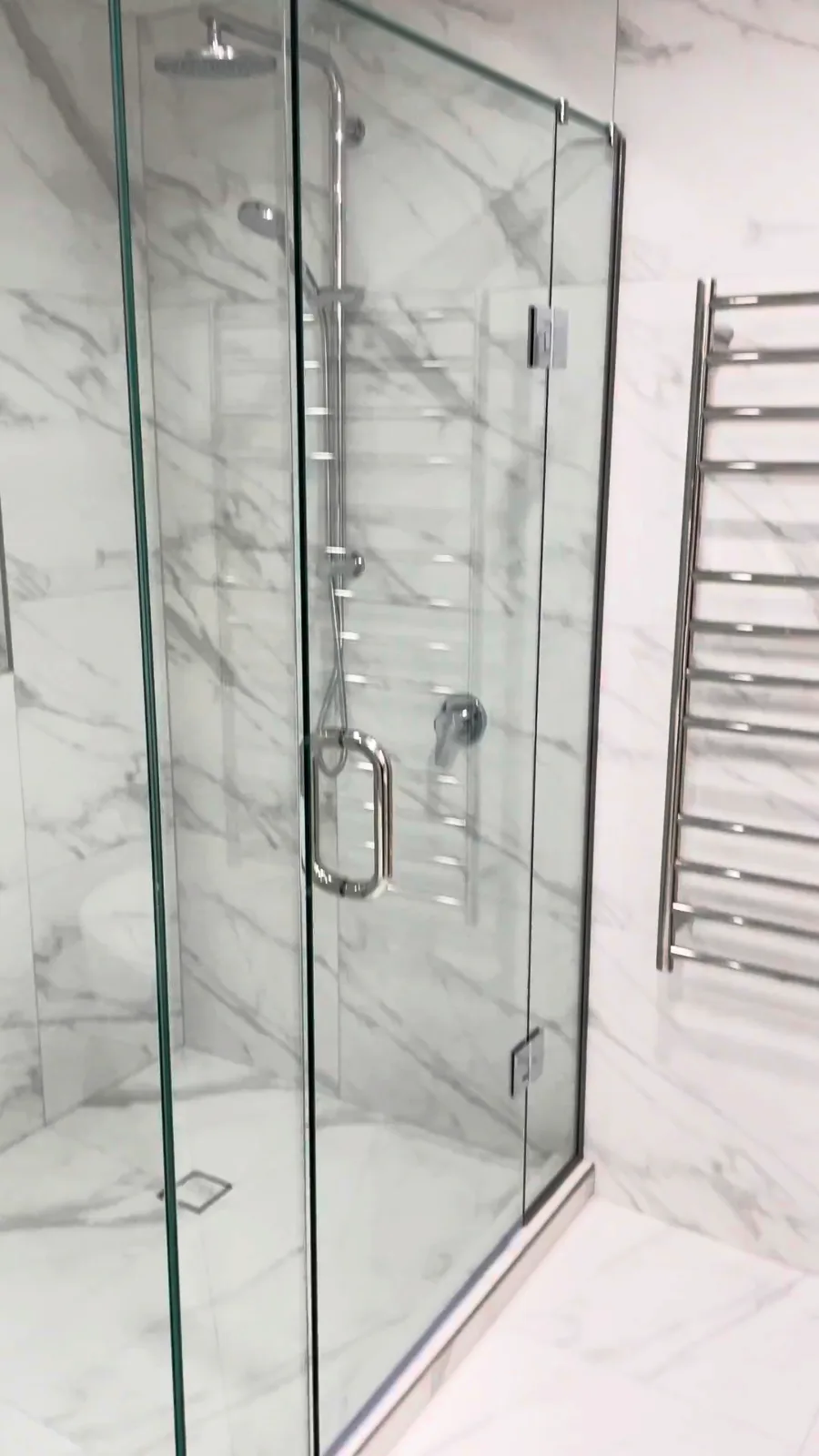 Stainless heated towel ladder beside a glass corner shower in a Kohimarama bathroom