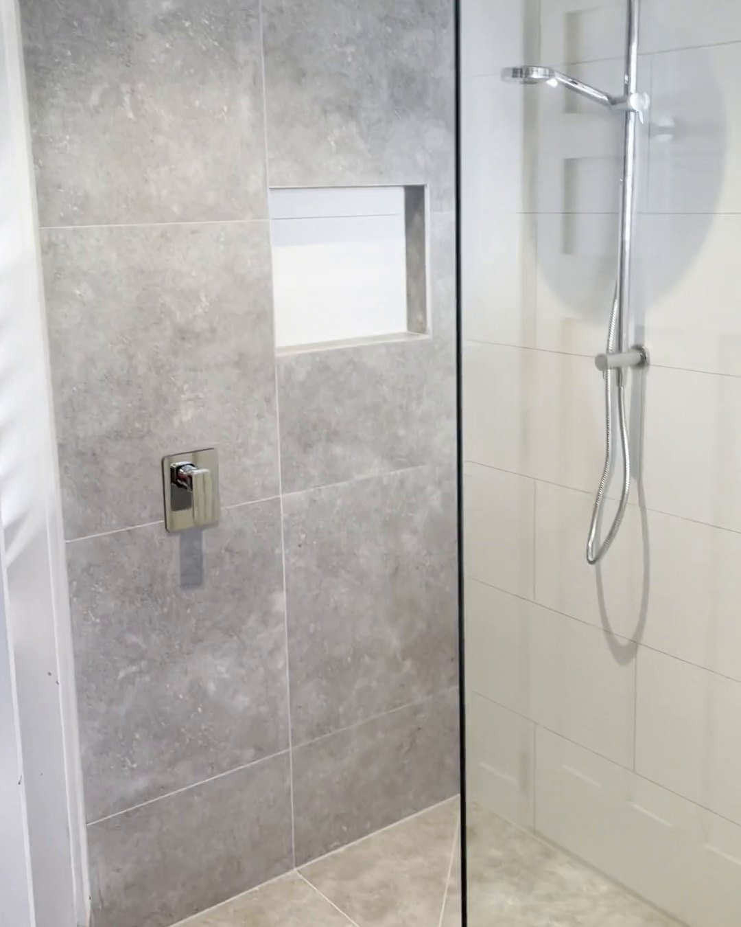 Walk-in shower with a frameless glass panel, rail shower and grey feature wall, Parnell