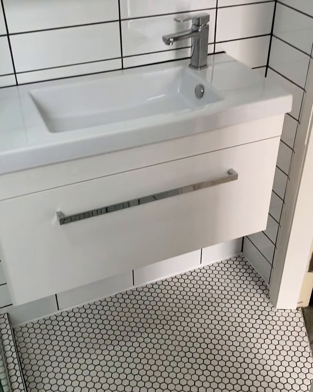 Ranui bathroom renovation vanity Wall-hung white vanity with a chrome mixer on a white hexagon mosaic floor, Ranui bathroom renovation