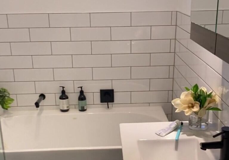 White bath with a matte black wall spout beside a white basin vanity, Albany bathroom renovation