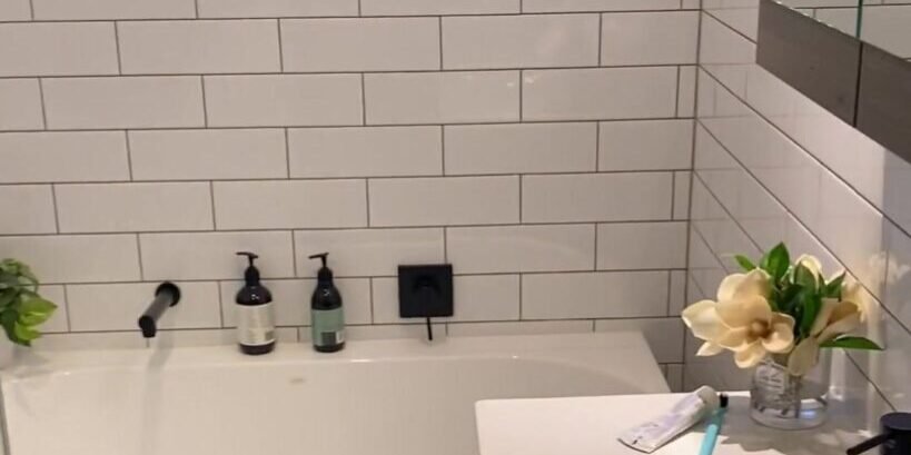 White bath with a matte black wall spout beside a white basin vanity, Albany bathroom renovation