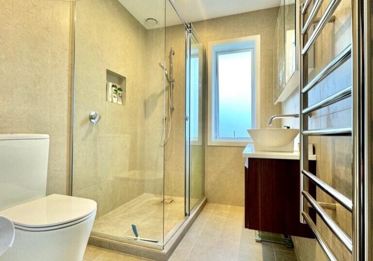 Finished bathroom with a corner glass shower, back-to-wall toilet and heated towel rail Finished bathroom with a corner glass shower, back-to-wall toilet and heated towel rail