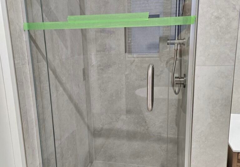 Frameless glass shower with a rain head and tiled niche, protective tape still on the glass Frameless glass shower with a rain head and tiled niche, protective tape still on the glass