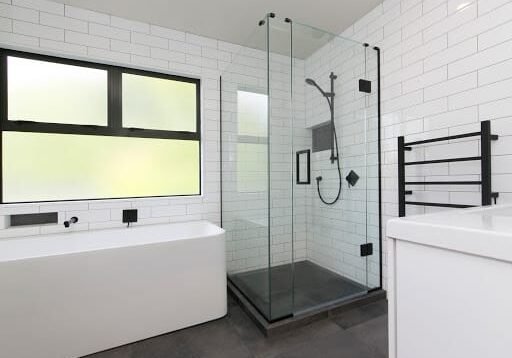 Glass shower with black hardware and a black heated towel rail in an Epsom bathroom