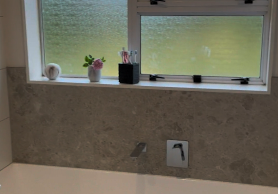 Bath under the window with a stone-look tiled splashback in a Botany bathroom