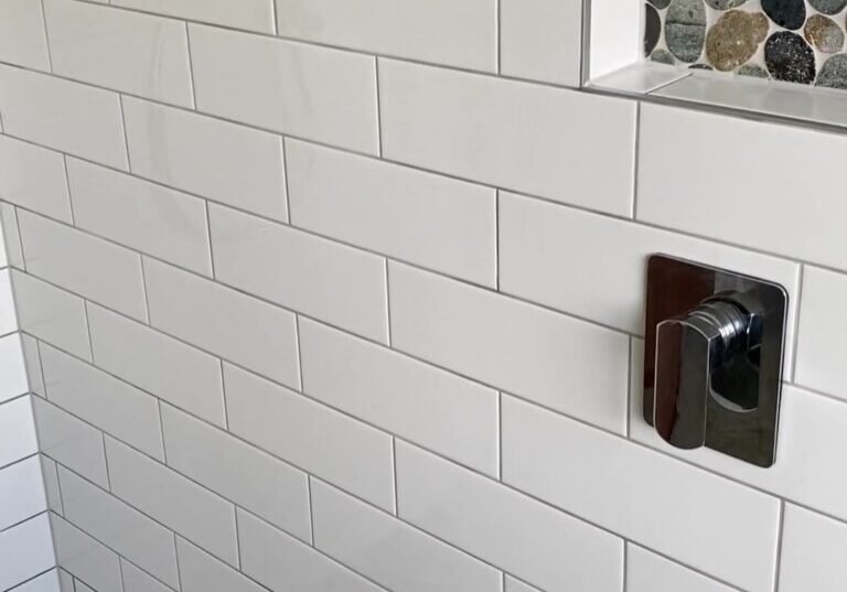 Two river-pebble shower niches and a low recess in white subway tiles, Cockle Bay bathroom