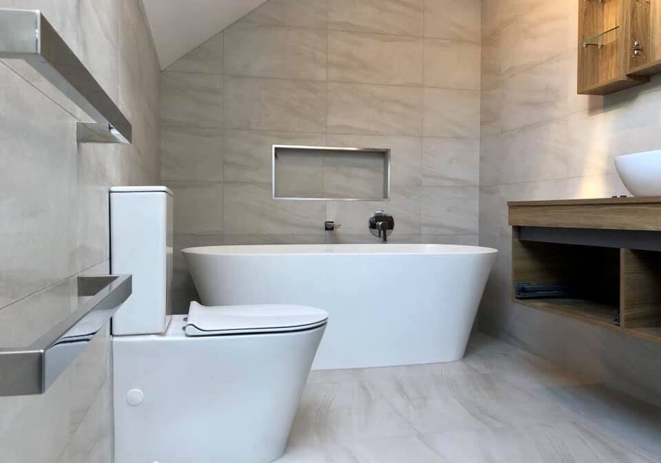 complete bathroom renovation auckland Freestanding bath under a sloped ceiling with a timber vanity in a Bayview family bathroom