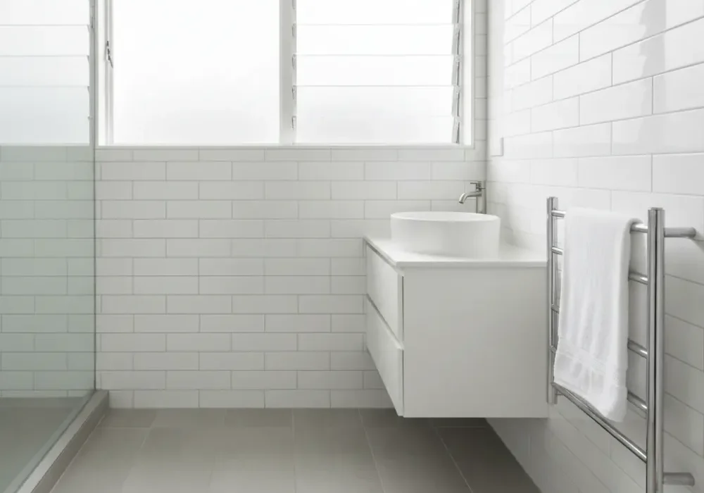 Completed Auckland ensuite renovation with grey stone-look tiles, white subway walls, vessel basin, and chrome heated towel rail.
