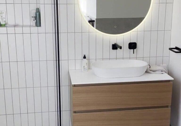 mount-eden-bathroom-vanity-mirror Wall-hung oak-look vanity with a vessel basin and a round backlit mirror, Mount Eden bathroom renovation