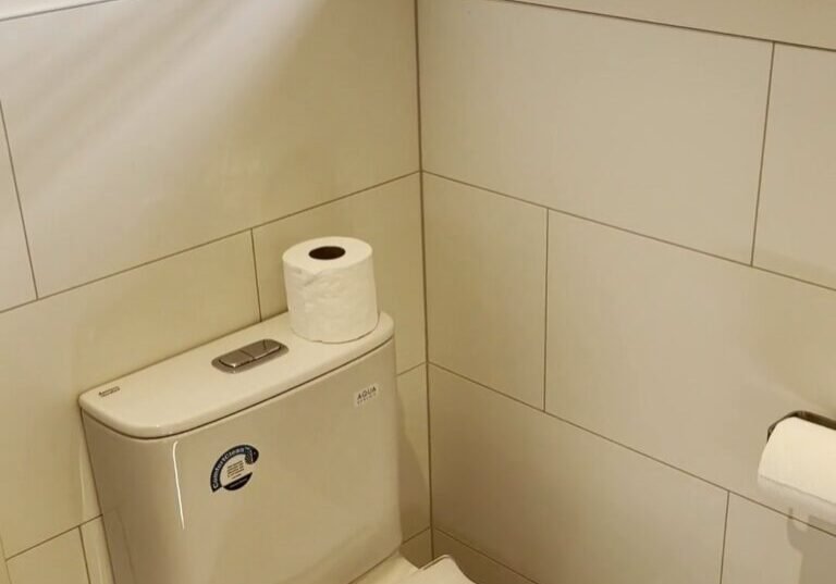 Parnell bathroom toilet under window Close-coupled toilet under a timber window with white brick-pattern wall tiles, Parnell bathroom