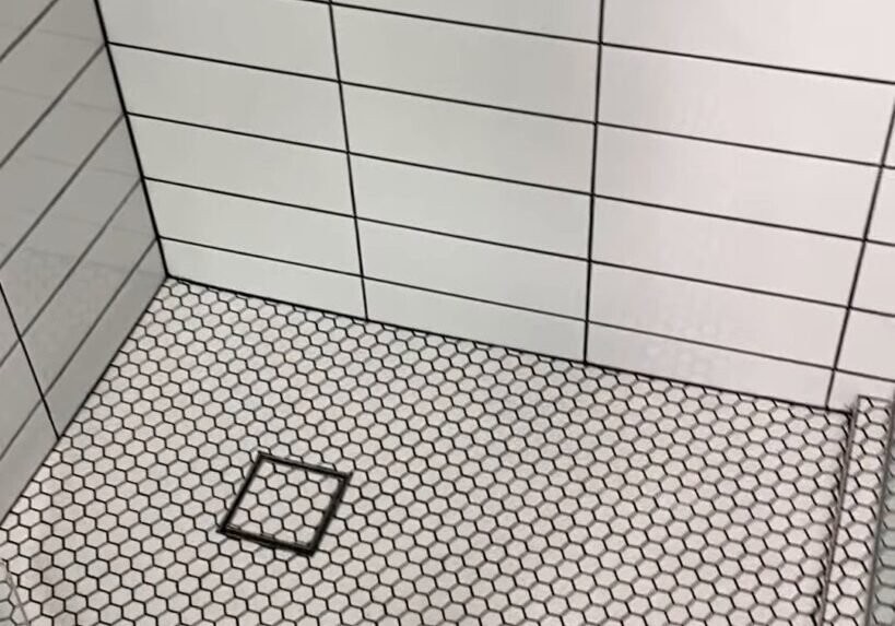 White hexagon mosaic shower floor with charcoal grout and a square chrome drain grate, Ranui