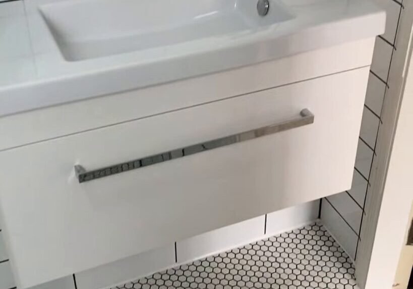Wall-hung white vanity with a chrome mixer on a white hexagon mosaic floor, Ranui bathroom renovation
