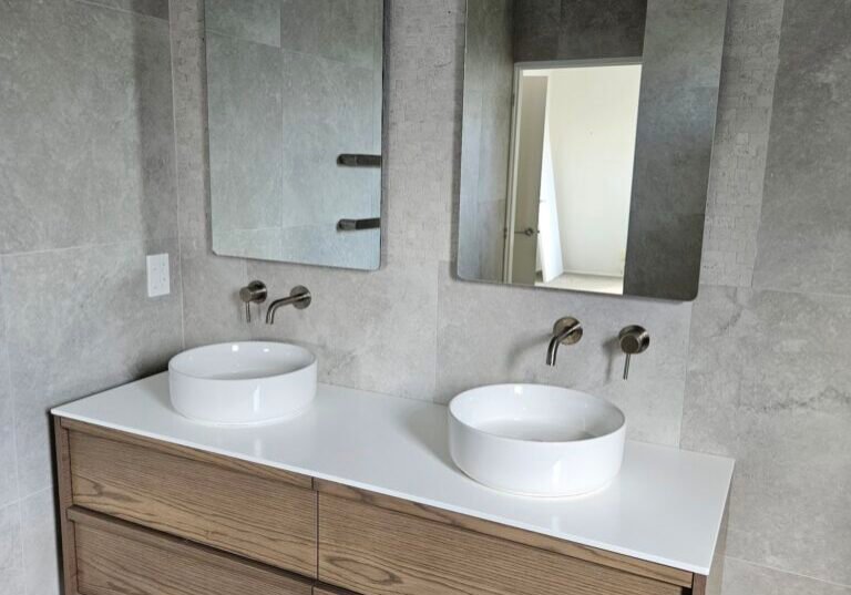 Floating timber double vanity with two round basins and arched mirrors in an Auckland bathroom renovated by Alchemy