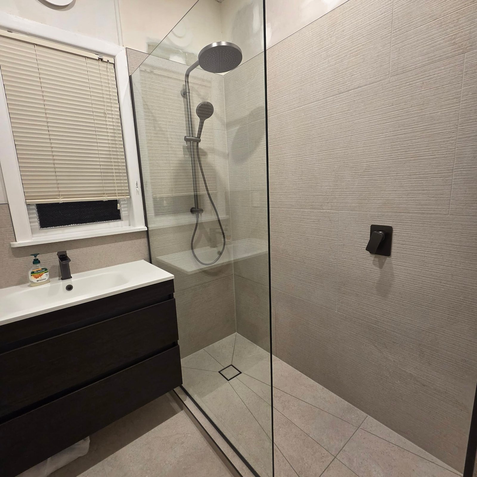Walk-in tiled shower with frameless glass, Auckland bathroom renovation Walk-in tiled shower with frameless glass and a dark wall-hung vanity in an Auckland bathroom renovated by Alchemy